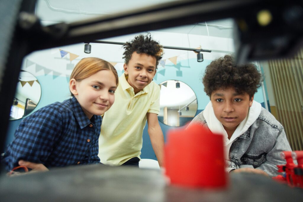 Two children watching a desktop 3D printer at work