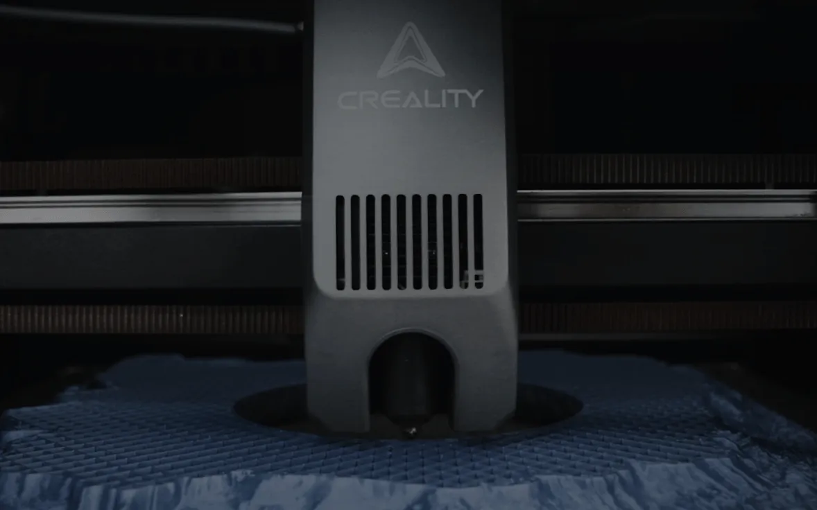 Close-up of the Creality K2 toolhead printing a blue part on the build plate